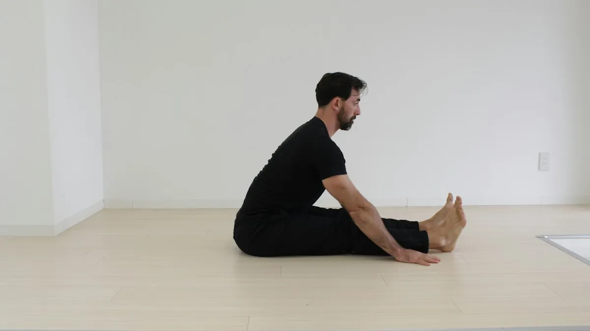 Hombre estirando la parte posterior de las piernas sentado en el suelo de una habitación luminosa