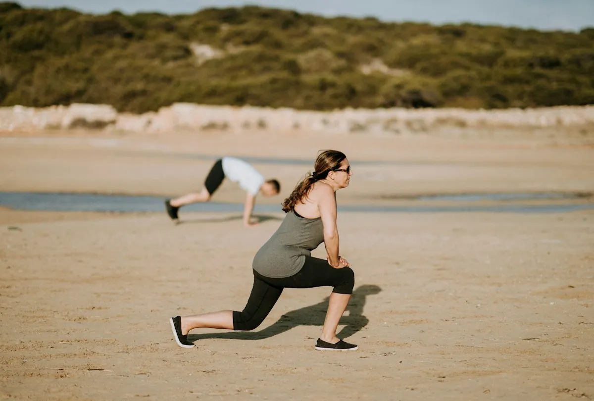 Mujer haciendo zancadas en la playa, parte de una rutina de 30 minutos que puedes hacer en casa o de viaje
