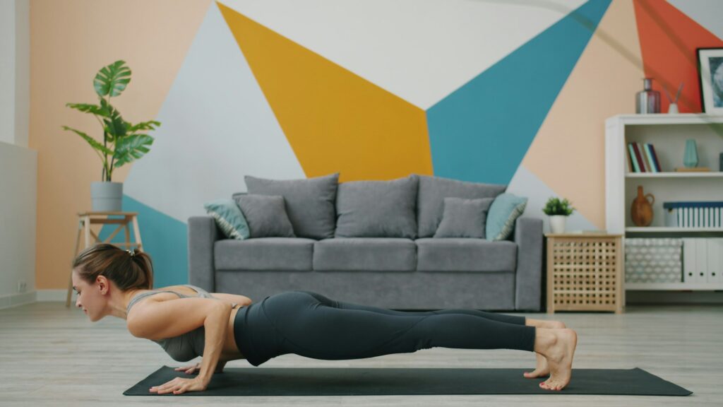 Mujer haciendo flexiones sobre una esterilla en el salón de su casa, sin material
